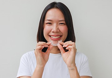 Woman smiling while holding clear aligner