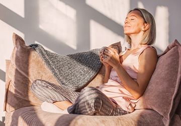 Woman smiling while enjoying tea on couch