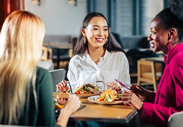 Group of friends smiling while eating at restaurant